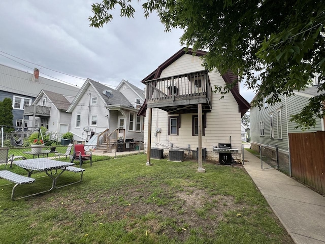 rear view of property with central air condition unit, a yard, and a balcony