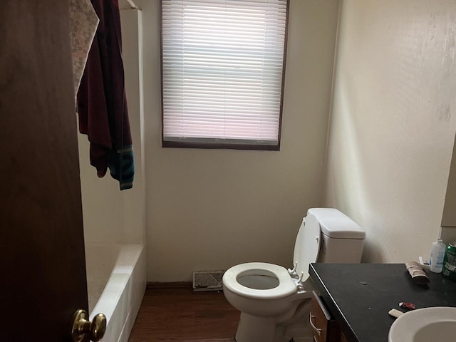 bathroom featuring a washtub, hardwood / wood-style floors, vanity, and toilet