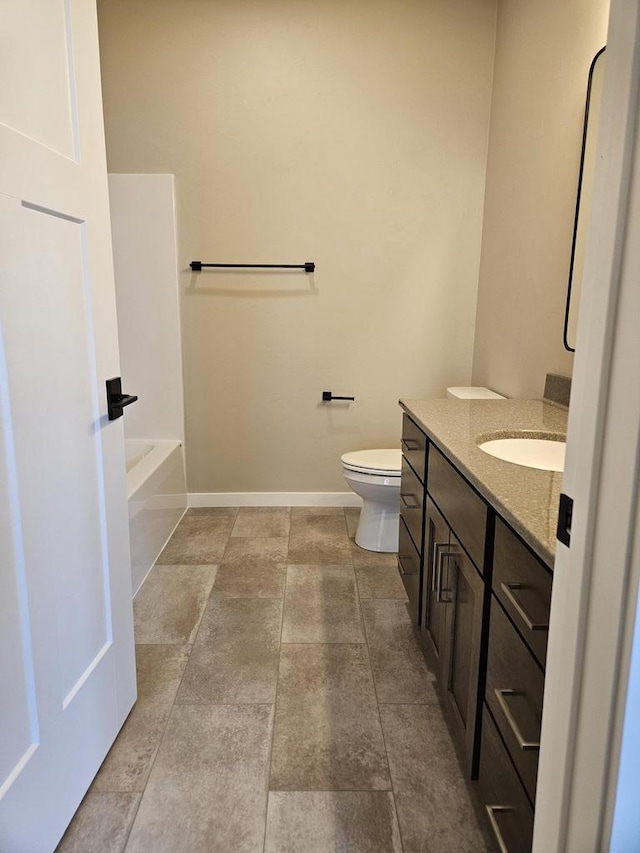 bathroom featuring vanity, a tub to relax in, and toilet