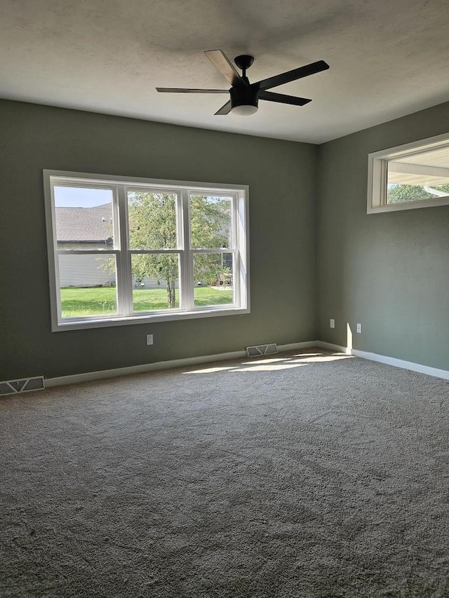 unfurnished room featuring plenty of natural light, ceiling fan, and carpet