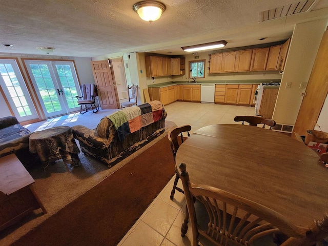 dining area featuring a textured ceiling, light tile patterned flooring, sink, and french doors