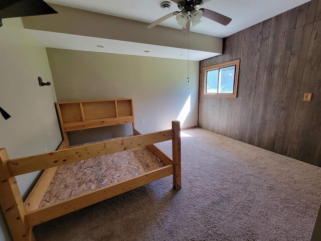 interior space featuring carpet floors, ceiling fan, and wood walls