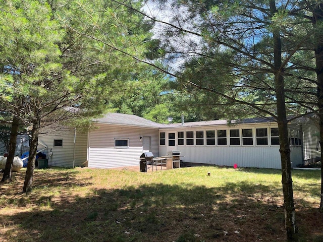 back of house featuring a lawn and a sunroom