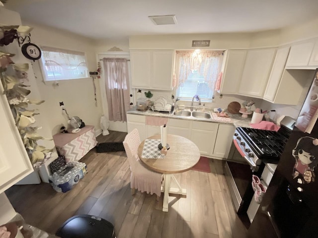 kitchen with white cabinets, high end stove, plenty of natural light, and sink