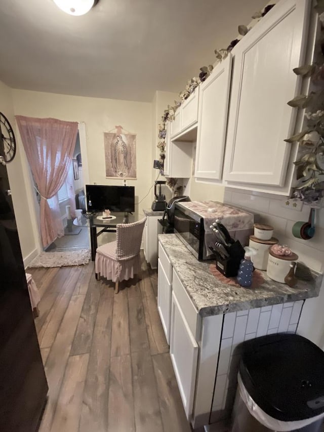 kitchen with white cabinets, dark hardwood / wood-style floors, and light stone counters