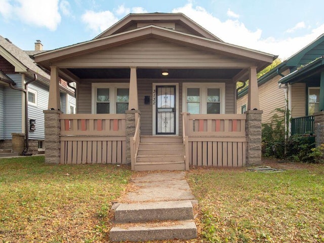 bungalow with covered porch and a front lawn