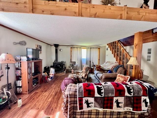 living room with a wood stove, wood-type flooring, and a textured ceiling