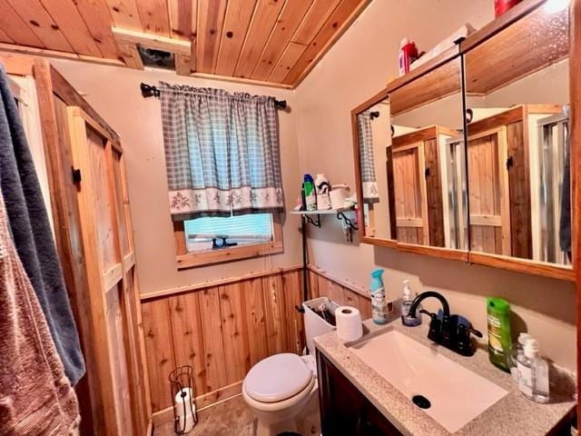 bathroom with ornamental molding, vanity, wooden walls, wooden ceiling, and toilet