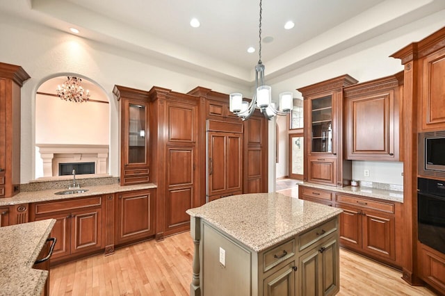 kitchen with light stone counters, sink, pendant lighting, a center island, and oven