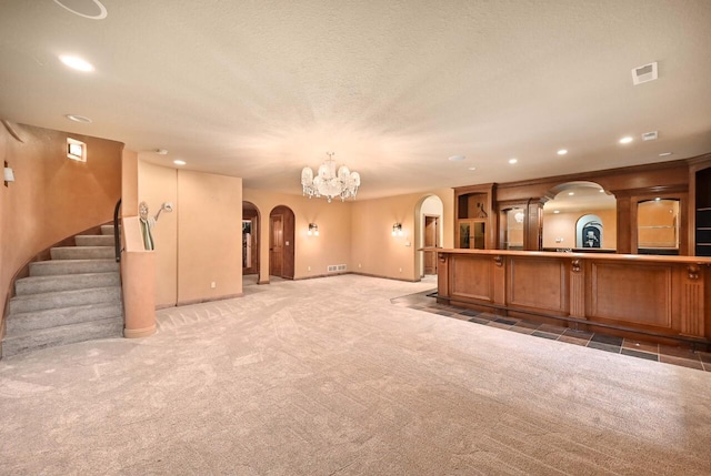 unfurnished living room with carpet flooring, a chandelier, and a textured ceiling