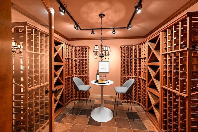 wine cellar with tile patterned flooring, ornamental molding, and track lighting