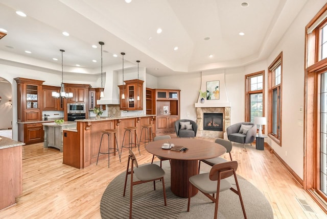 dining area featuring light wood-type flooring, a tray ceiling, and an inviting chandelier