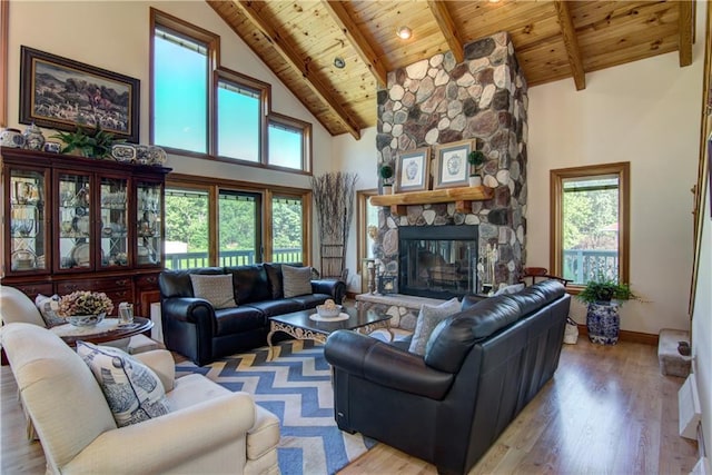 living room with a stone fireplace, beamed ceiling, wood ceiling, and light hardwood / wood-style floors