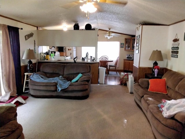 living room with ornamental molding, a textured ceiling, ceiling fan, lofted ceiling, and wood walls