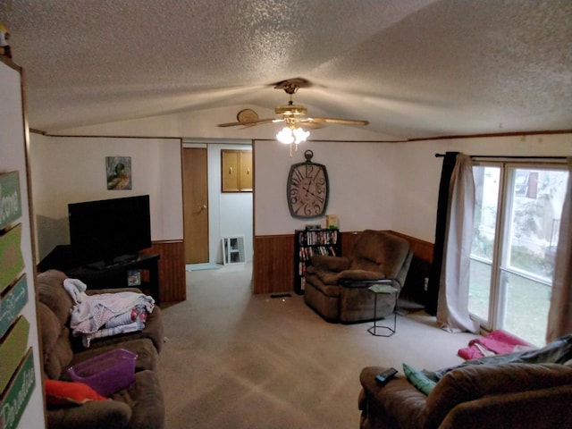 carpeted living room with lofted ceiling, wooden walls, ceiling fan, and a textured ceiling