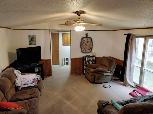 living room featuring ceiling fan, light colored carpet, vaulted ceiling, a textured ceiling, and wooden walls