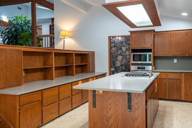 kitchen with appliances with stainless steel finishes, a kitchen island, and lofted ceiling