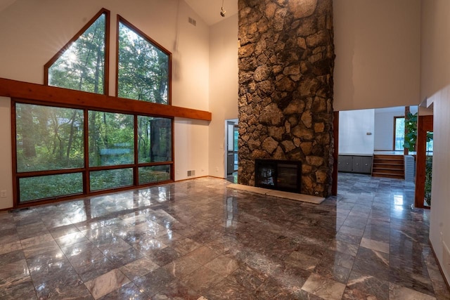 unfurnished living room featuring a high ceiling and a stone fireplace