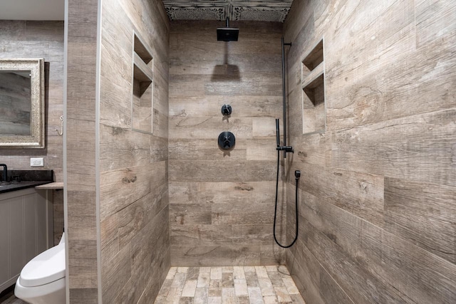 bathroom featuring a tile shower, vanity, and toilet