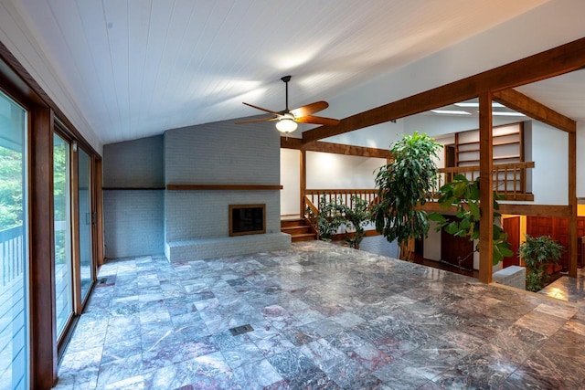 living room featuring ceiling fan, lofted ceiling, brick wall, and a brick fireplace