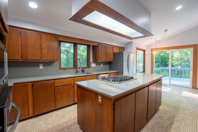 kitchen featuring sink, stainless steel appliances, plenty of natural light, vaulted ceiling, and a kitchen island