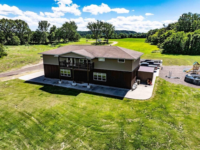 back of property featuring a rural view, a patio area, a yard, and a wooden deck