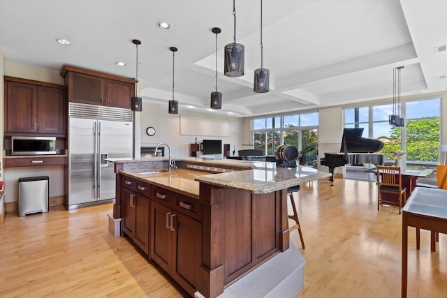 kitchen with appliances with stainless steel finishes, hanging light fixtures, a large island, and sink