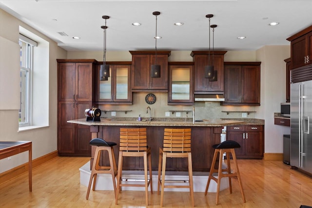 kitchen featuring pendant lighting, a kitchen bar, and light stone counters