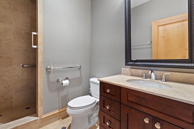 bathroom with a tile shower, vanity, and toilet