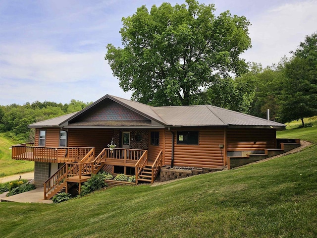 rear view of property with a wooden deck and a lawn