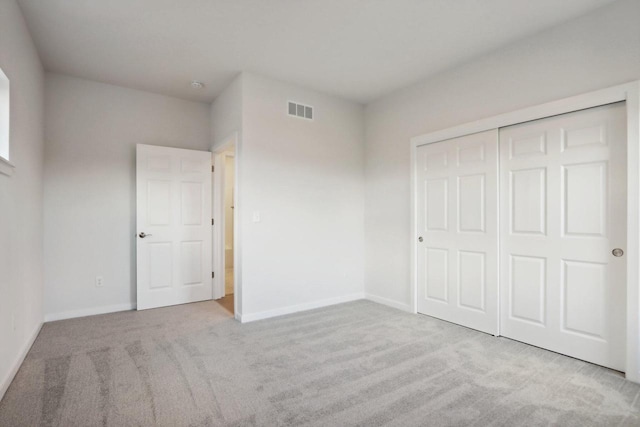 unfurnished bedroom featuring a closet and light colored carpet