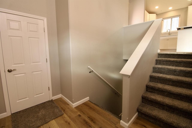 stairs featuring sink and hardwood / wood-style flooring