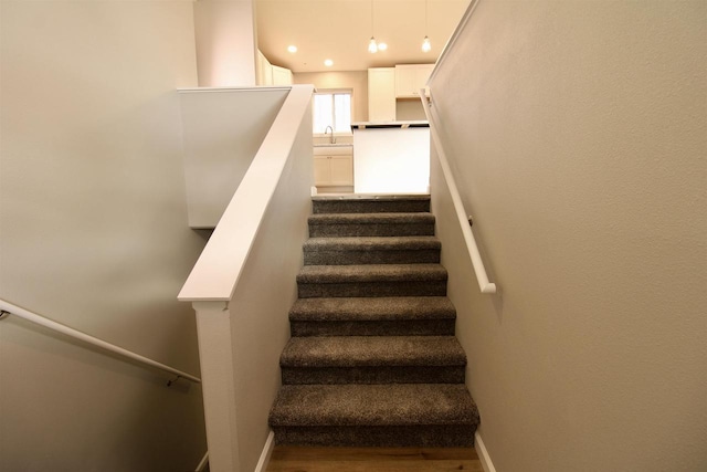 staircase featuring wood-type flooring and sink