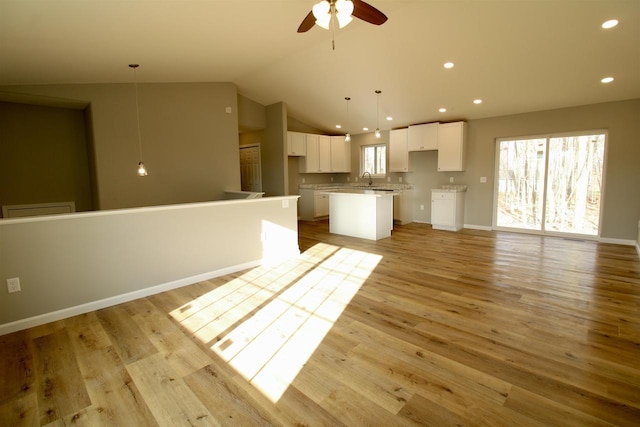 unfurnished living room with ceiling fan, light hardwood / wood-style floors, lofted ceiling, and sink