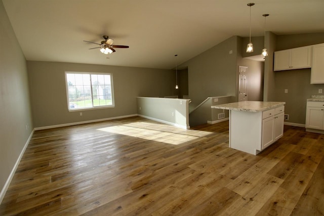 kitchen with white cabinets, pendant lighting, a center island, and vaulted ceiling