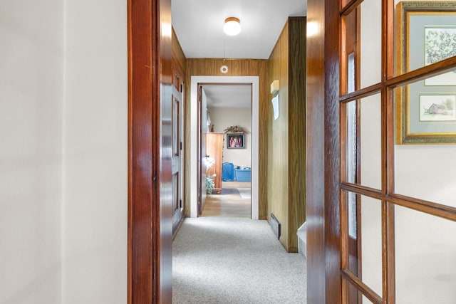 hallway featuring carpet flooring and wood walls