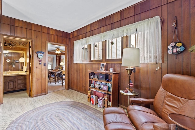 living area featuring ceiling fan and wood walls