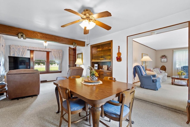 dining room featuring beam ceiling, light colored carpet, and ceiling fan