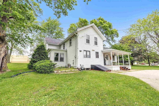 back of house with covered porch and a yard