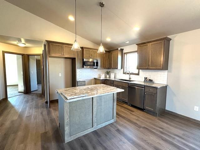 kitchen featuring a center island, stainless steel appliances, pendant lighting, vaulted ceiling, and decorative backsplash