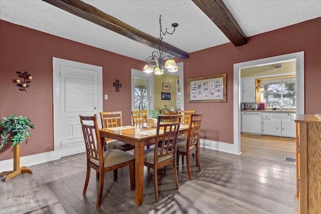 dining room with beam ceiling, light hardwood / wood-style floors, a textured ceiling, and a chandelier