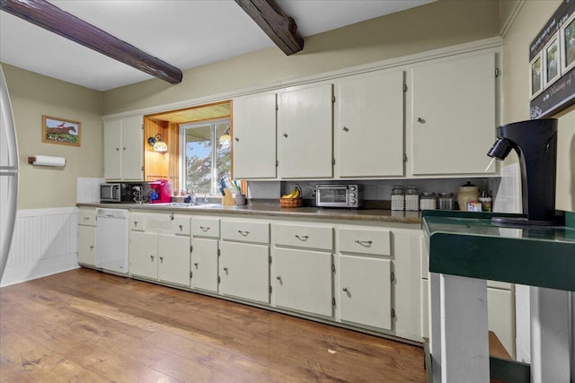 kitchen featuring dishwasher, sink, beamed ceiling, light hardwood / wood-style floors, and white cabinetry