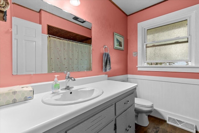 bathroom with crown molding, hardwood / wood-style floors, vanity, and toilet