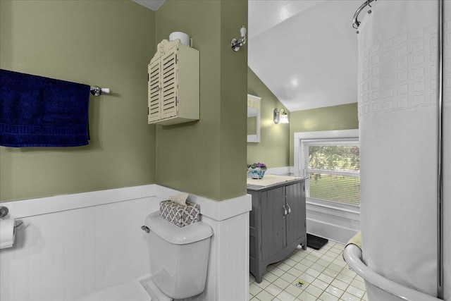 bathroom with tile patterned floors, vanity, toilet, and vaulted ceiling