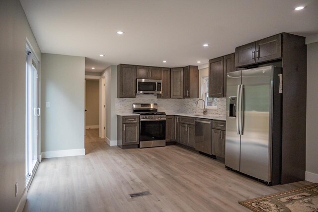 N9351 Juneau Ln, Necedah, WI 54646 - kitchen with decorative backsplash, dark brown cabinets, stainless steel appliances, and light hardwood / wood-style floors