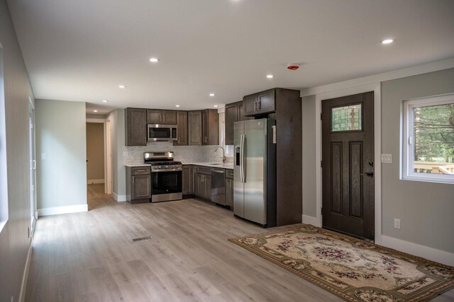N9351 Juneau Ln, Necedah, WI 54646 - kitchen featuring decorative backsplash, appliances with stainless steel finishes, dark brown cabinets, sink, and light hardwood / wood-style floors