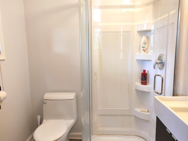 bathroom featuring vanity, toilet, and a shower with door