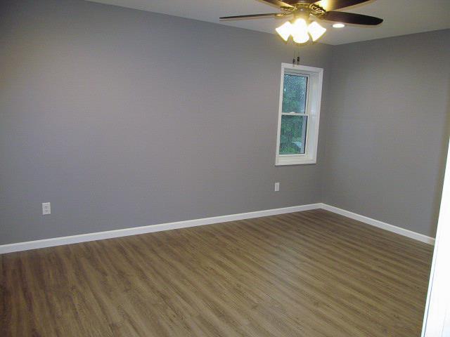 empty room with ceiling fan and dark hardwood / wood-style flooring