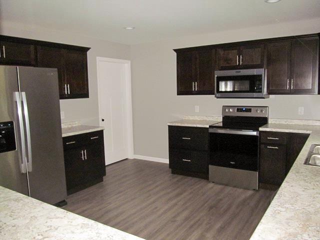 kitchen featuring appliances with stainless steel finishes, dark hardwood / wood-style flooring, and dark brown cabinetry