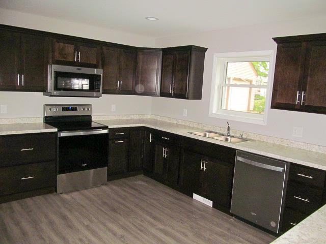 kitchen featuring wood-type flooring, sink, dark brown cabinetry, and stainless steel appliances